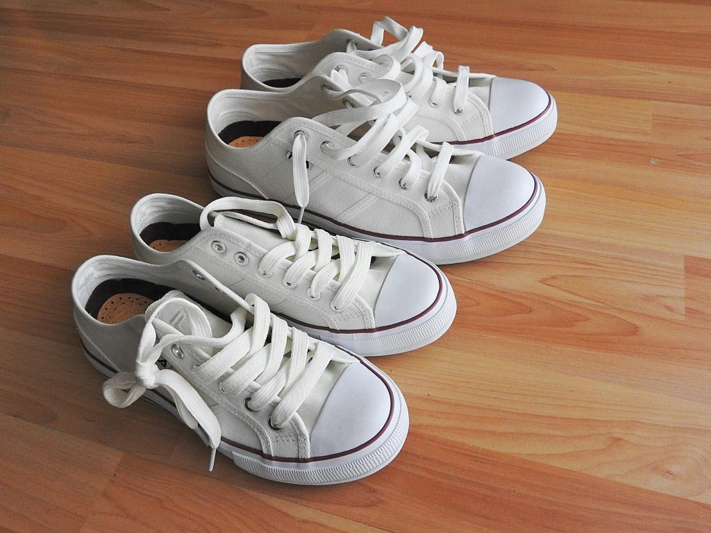 Pair of white sneakers on a clean wooden floor, casual and sporty look.